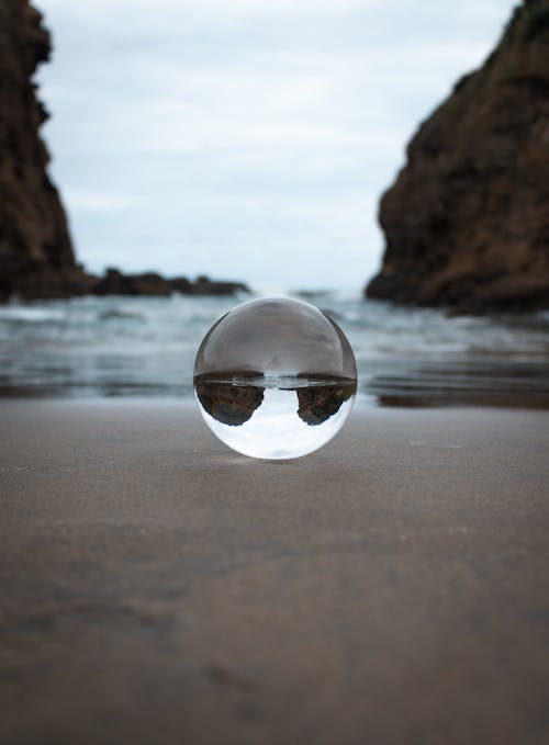 Clear Glass Ball with Reflection on Gray Sand