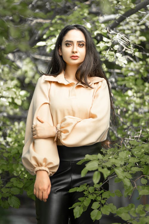 Woman in Beige Long Sleeves Standing Beside Green Plants