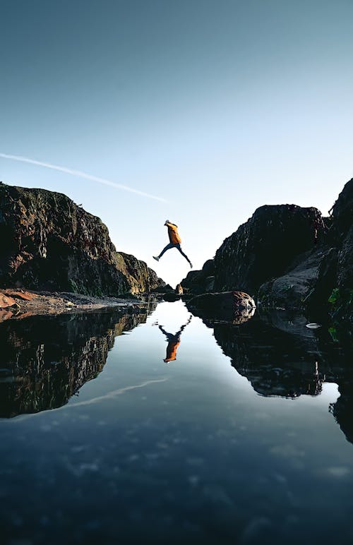 Person Jumping from A Rock