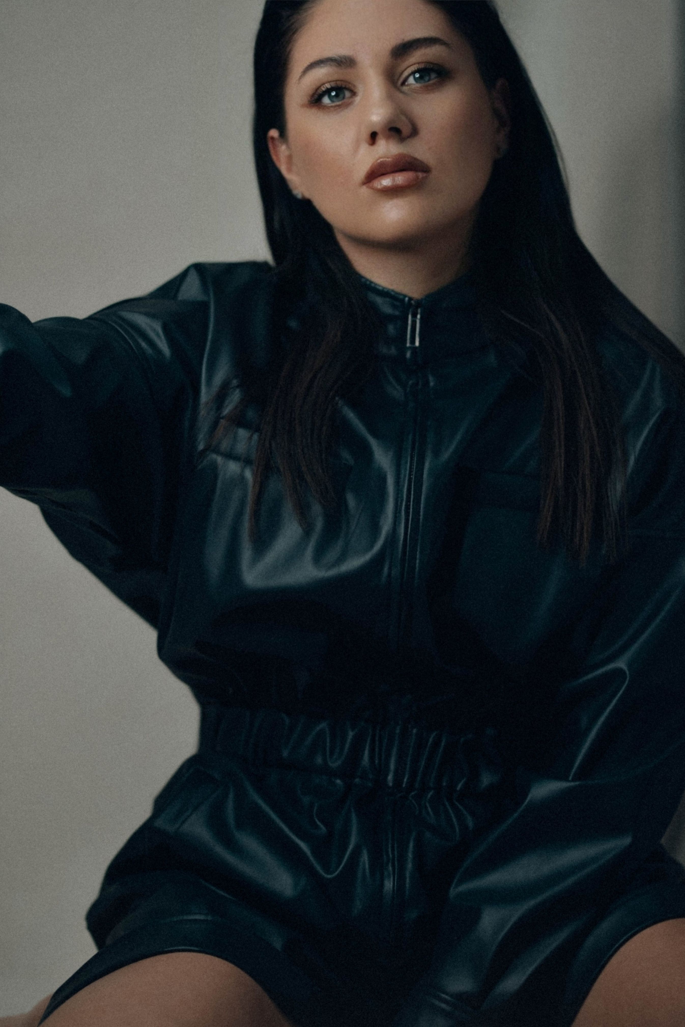 Portrait of a woman in a black leather outfit with a serious expression.