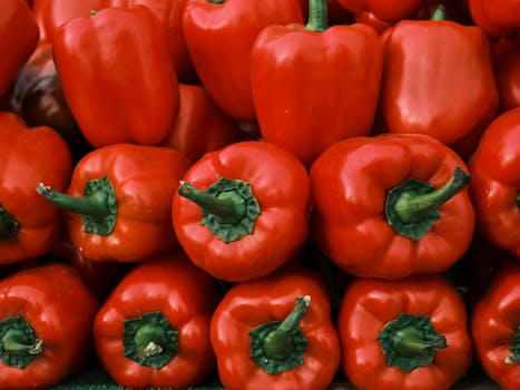 Close-up image of fresh red bell peppers stacked together, showcasing their vivid color.
