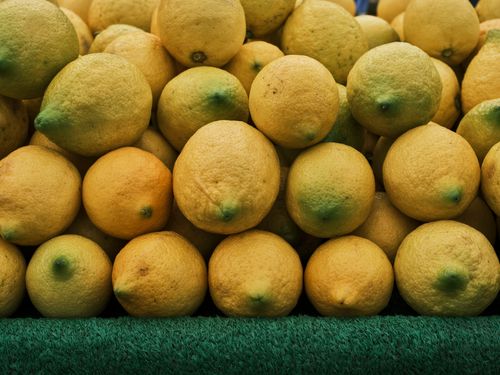 Free Close-up of fresh lemons stacked neatly on a green surface, showcasing vibrant citrus fruits. Stock Photo