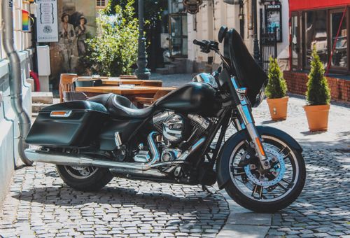 Free A Harley-Davidson motorcycle parked on a sunny cobblestone street with potted plants nearby. Stock Photo