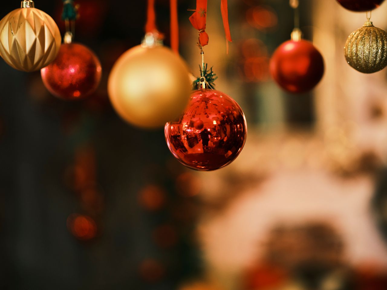 close up of shiny red and gold christmas ornaments hanging indoors cap