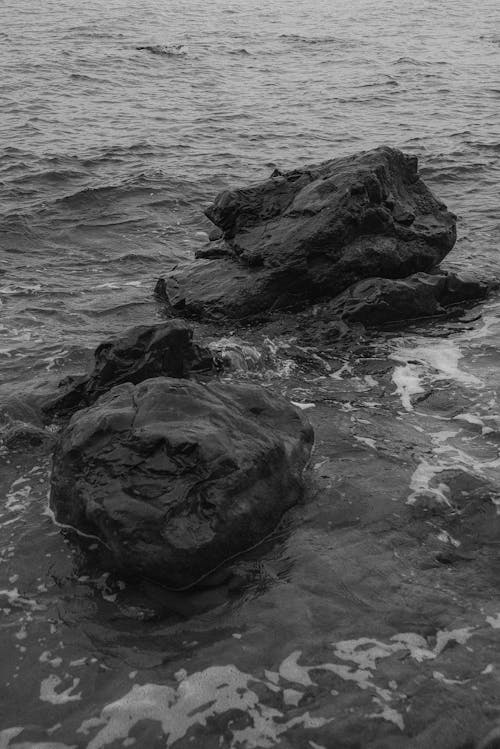 Grayscale Photo of Big Rocks in the Ocean 