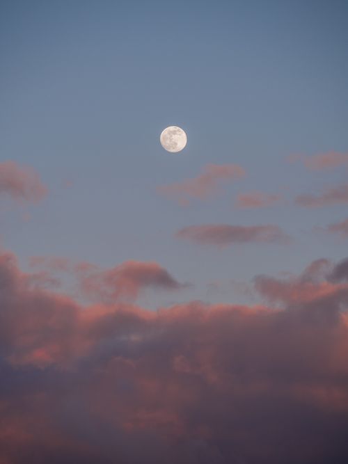 Free Beautiful full moon surrounded by vibrant clouds at dusk, capturing a serene sky scene. Stock Photo