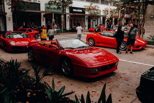 Dynamic street scene with luxury red convertibles at a public car show.