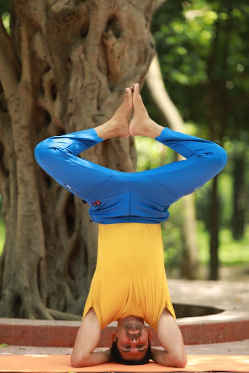 Man in Yellow Shirt and Blue Pants Doing a Headstand