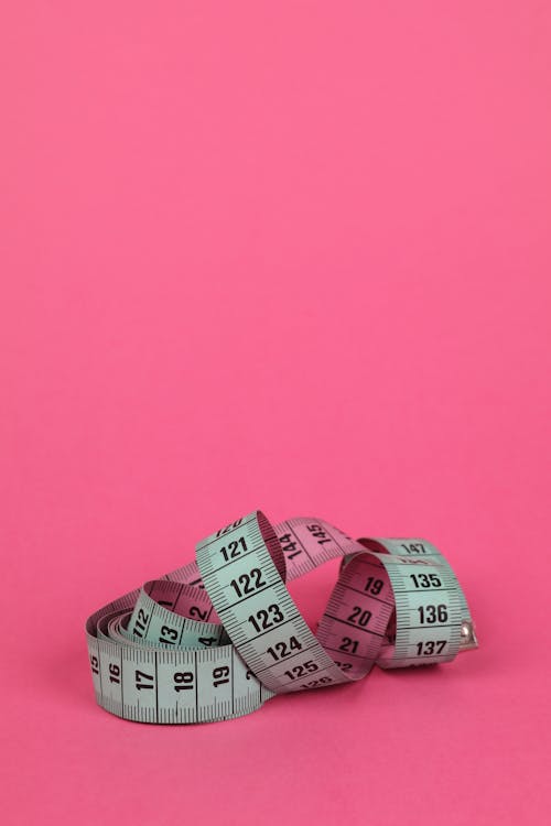 Rolled Tape Measure on Pink Background 