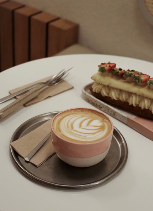 Free A cappuccino with latte art and a gourmet pastry on a table, creating a cozy cafe vibe. Stock Photo