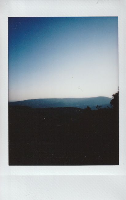 A tranquil view of mountains silhouetted against a fading blue sky at twilight.