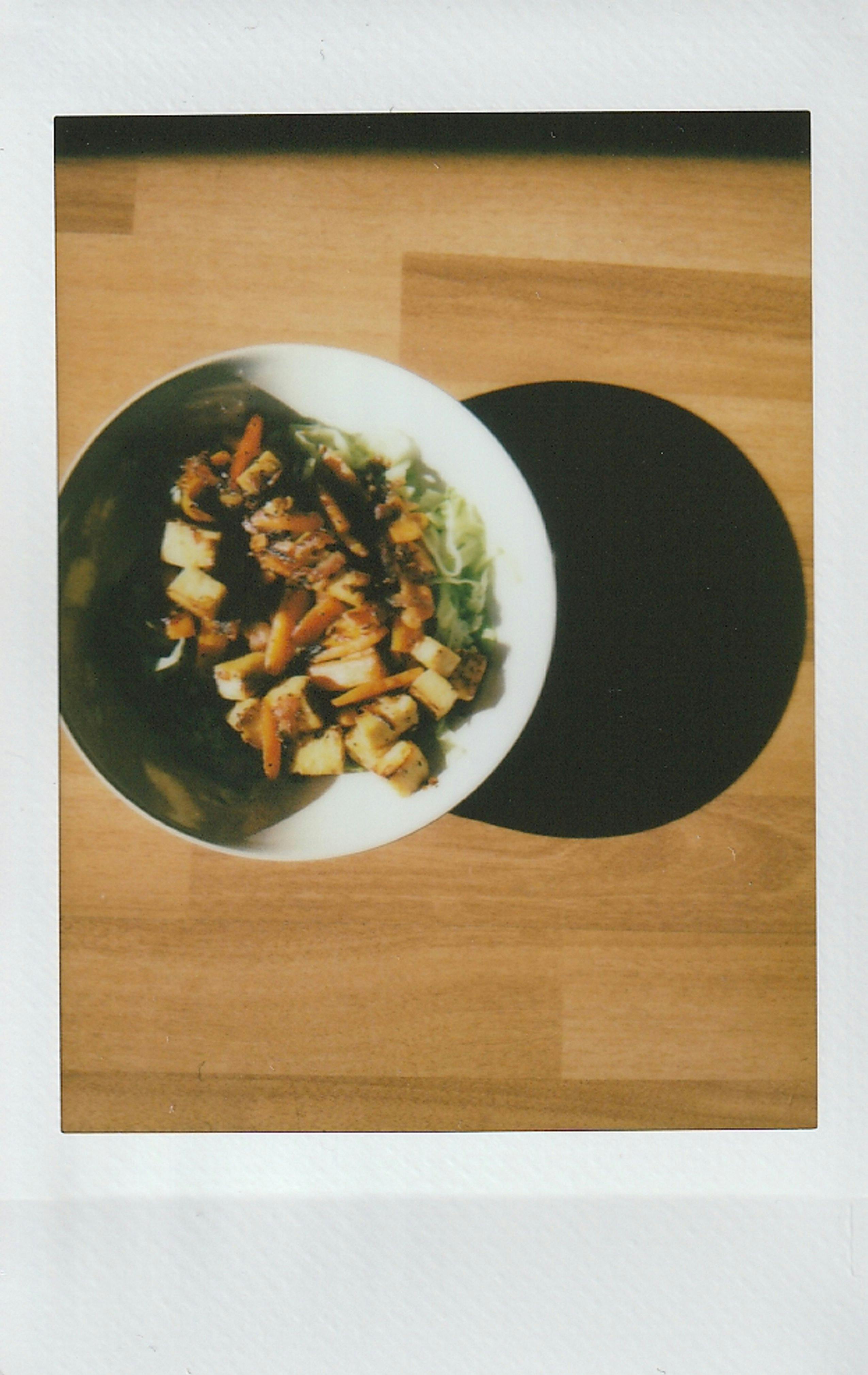 Polaroid instant capture of a tofu and vegetable vegan dish on a wooden table.