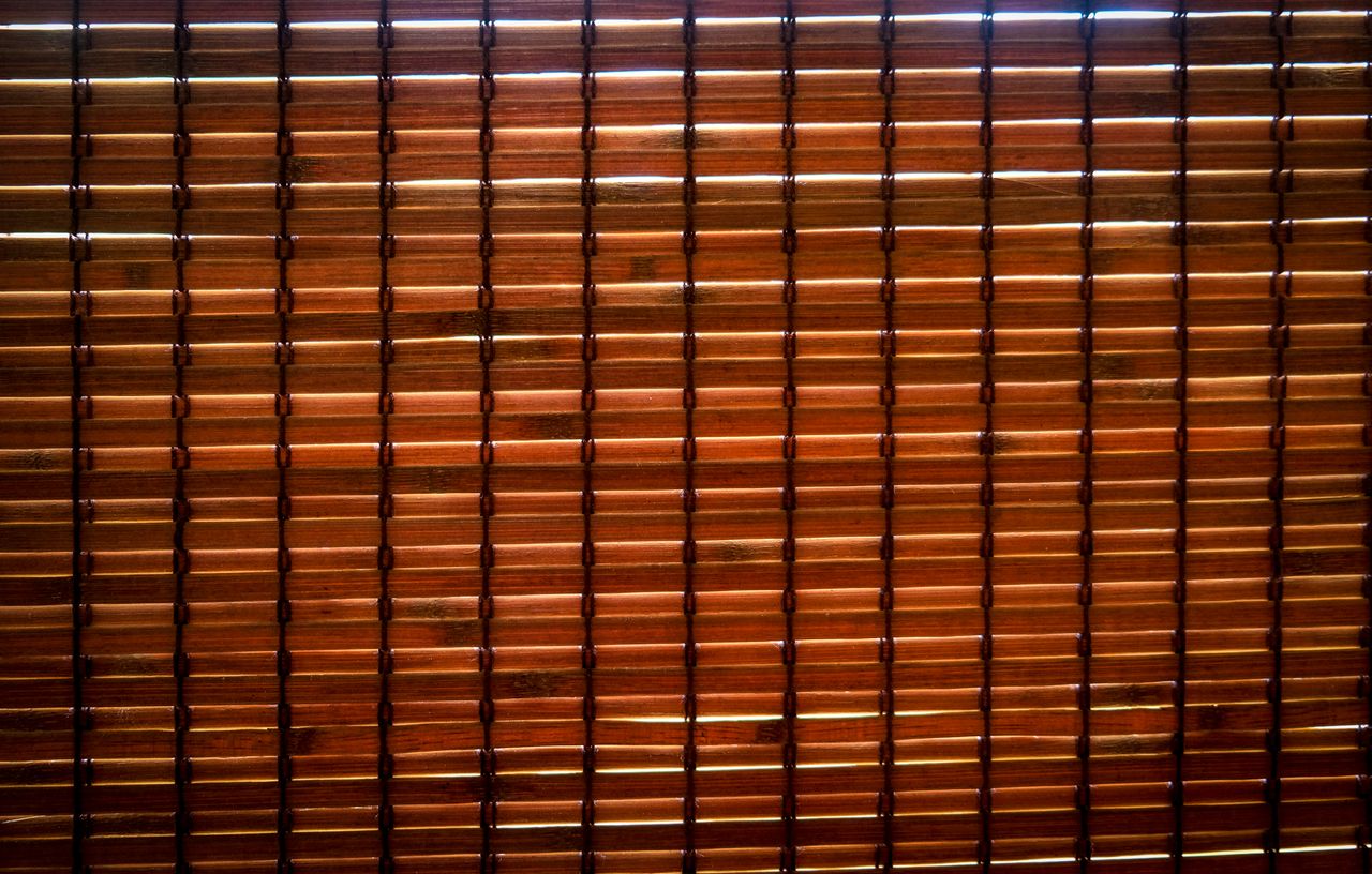 Close-up of a woven bamboo blind with warm sunlight filtering through the natural wood slats