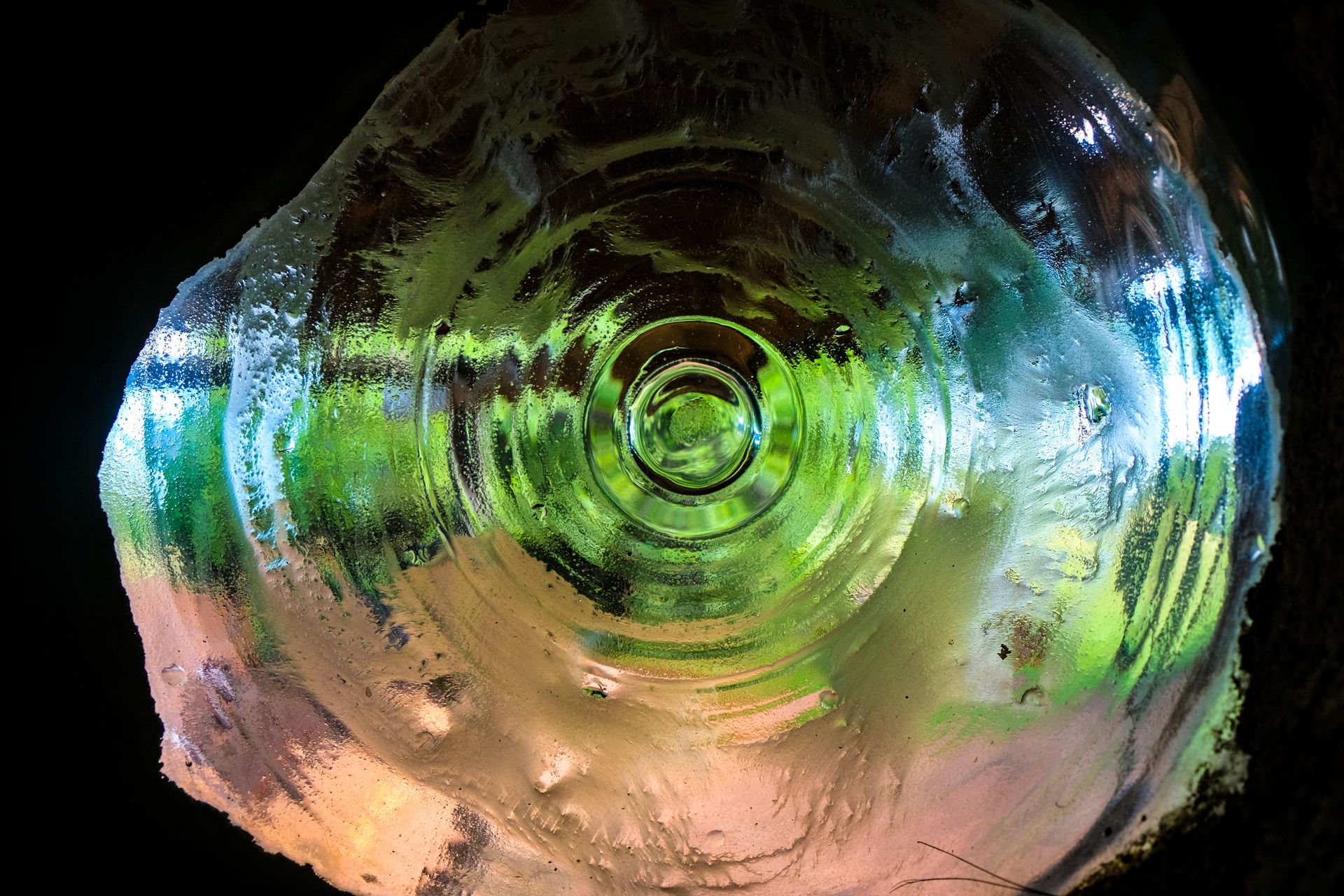 Abstract image showcasing the frosted base of a glass bottle with colorful lighting reflection.
