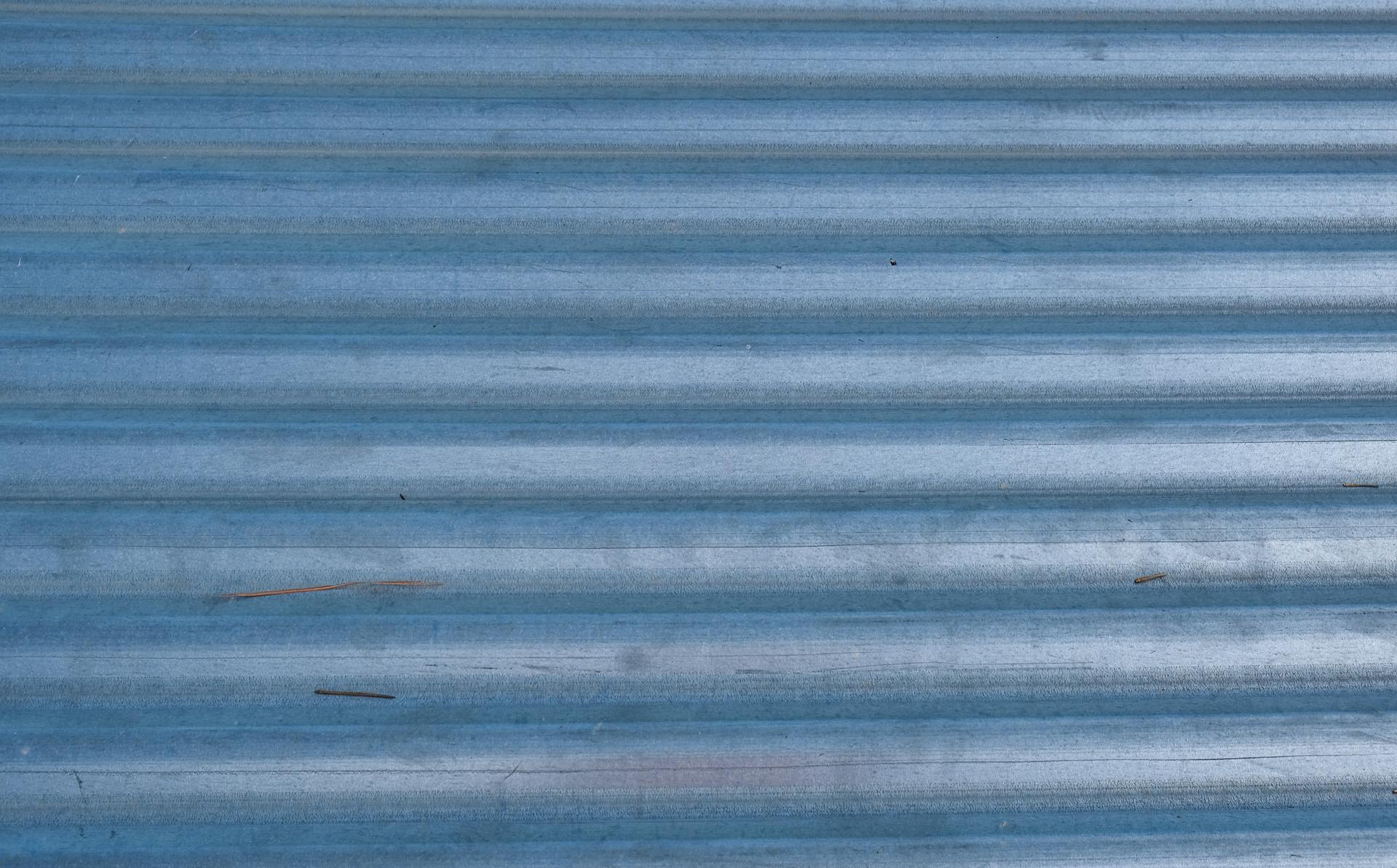 Close-up of corrugated blue metal surface with texture patterns, perfect for backgrounds.