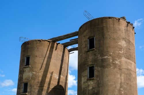 Free Two old, abandoned concrete silos stand tall against a clear blue sky. Stock Photo