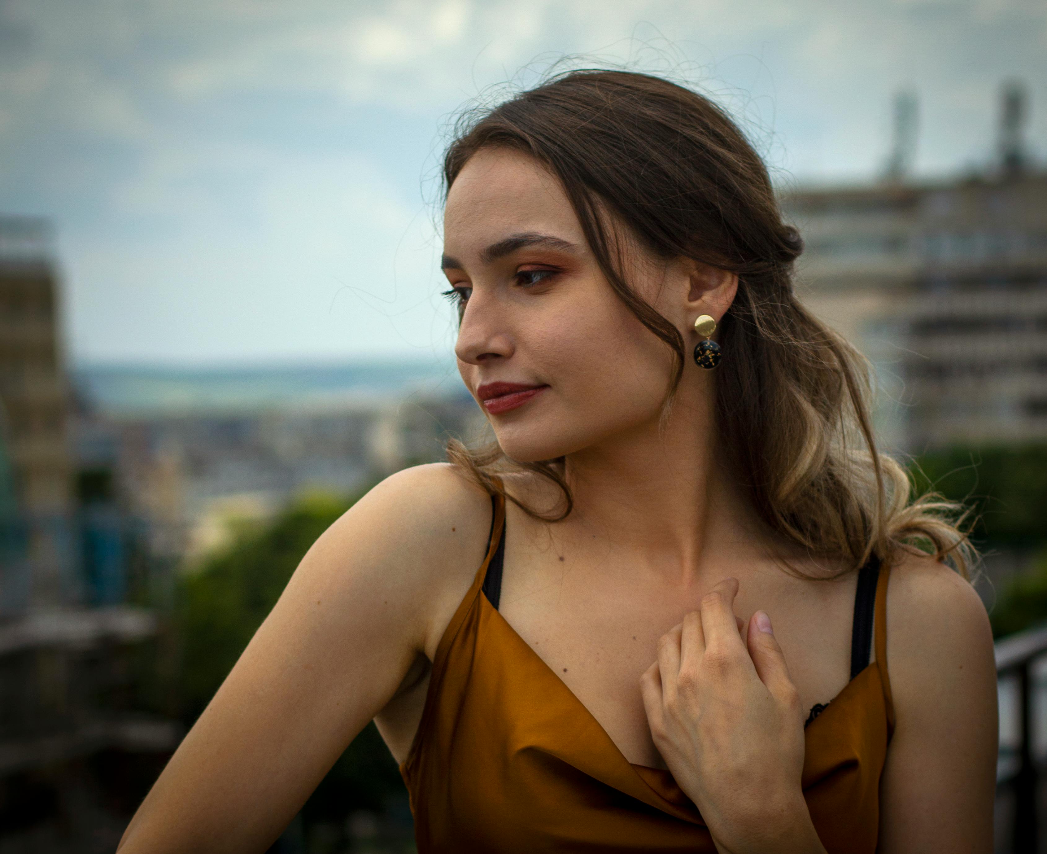 a beautiful woman in spaghetti strap top and gold earrings