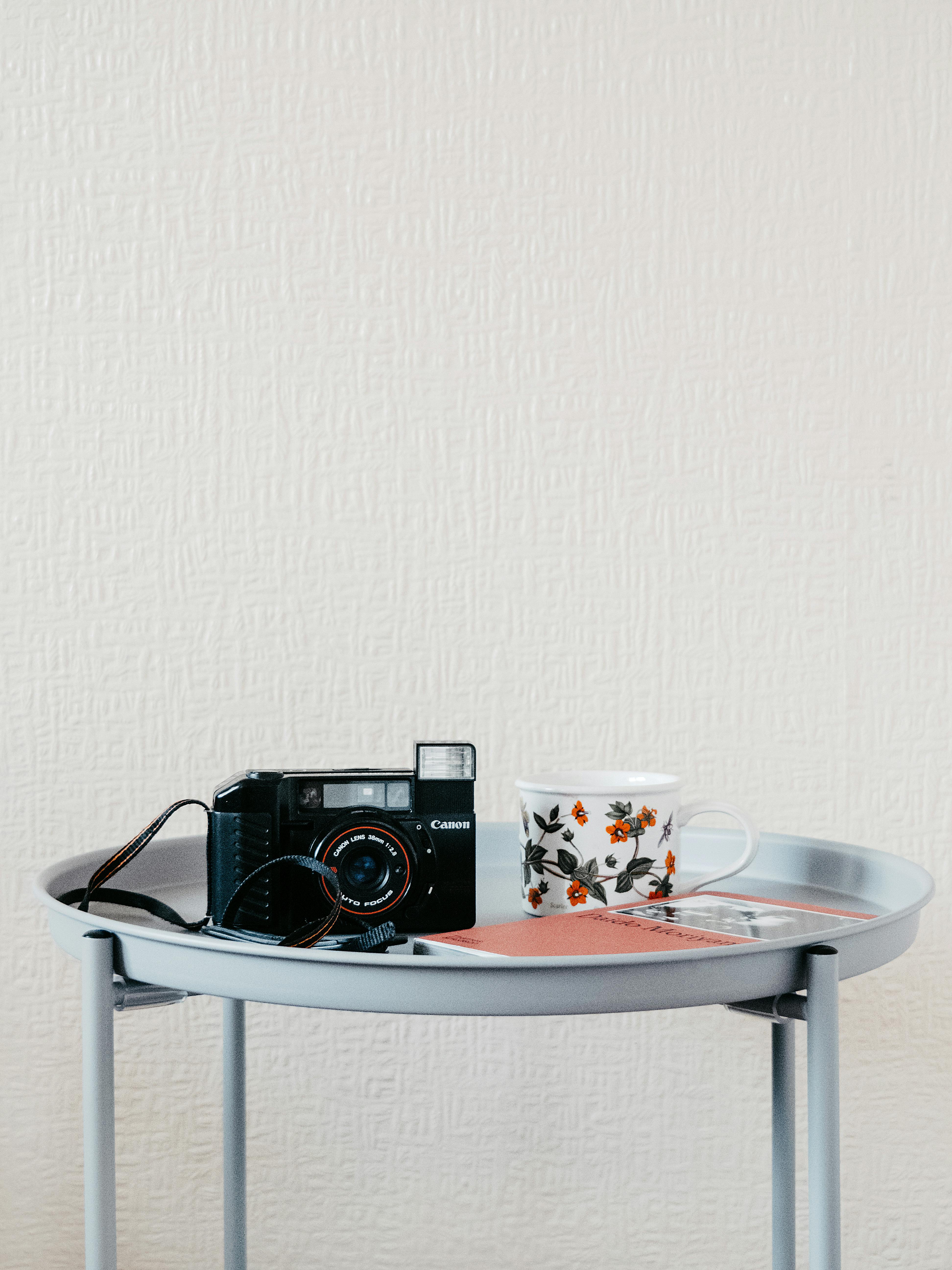 A classic camera and floral mug on a modern round table convey a blend of nostalgia and contemporary style.