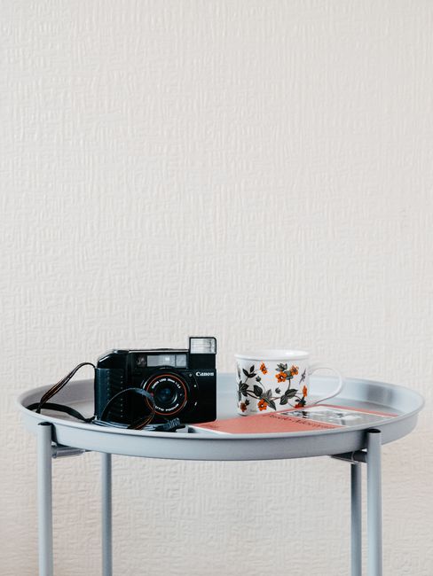 A classic camera and floral mug on a modern round table convey a blend of nostalgia and contemporary style.