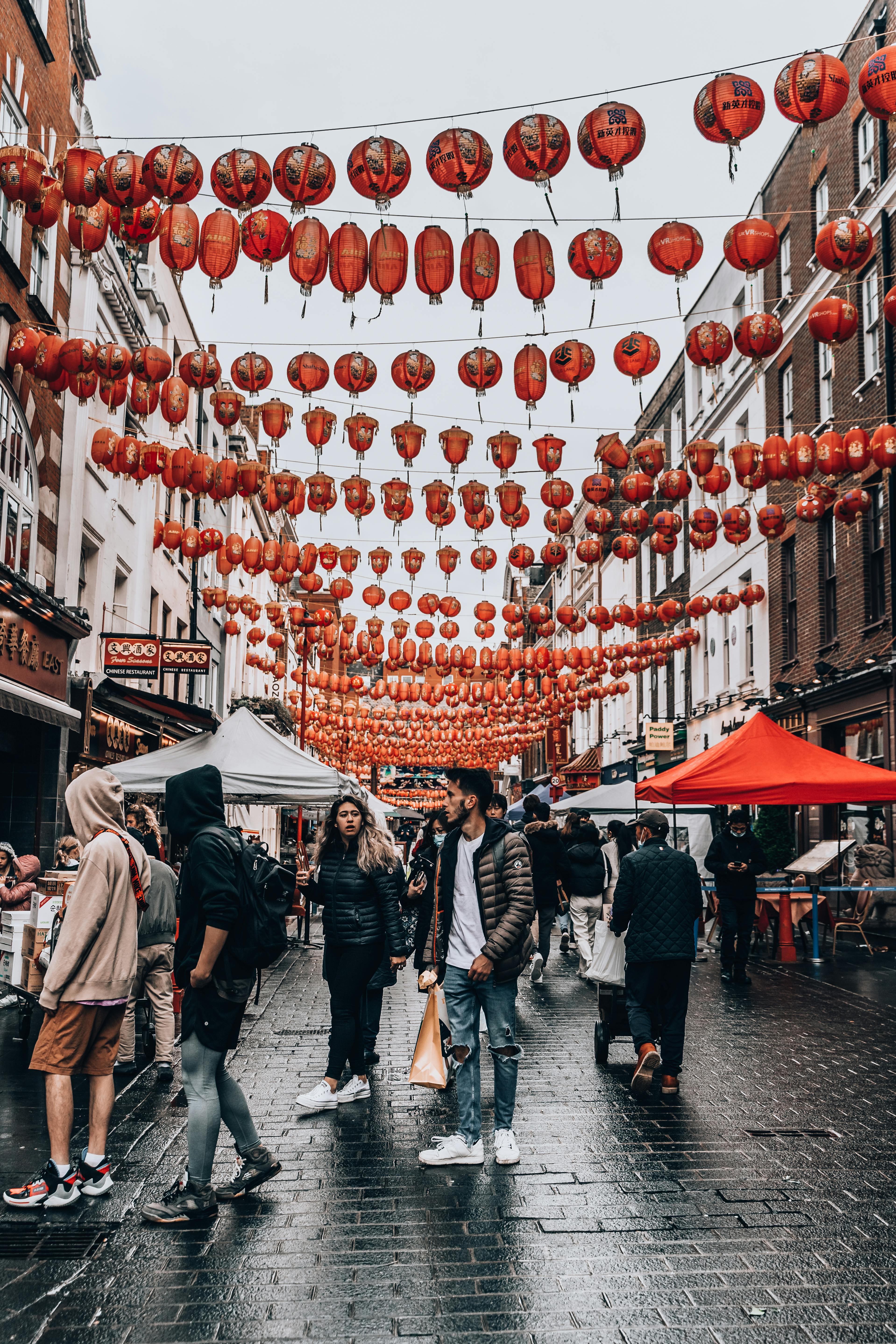 Bustling street adorned with red Chinese lanterns in London's Chinatown, capturing lively city life.