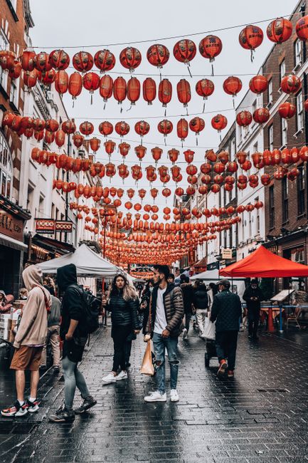 Bustling street adorned with red Chinese lanterns in London's Chinatown, capturing lively city life.