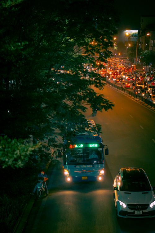 Free A bustling city road at night showcasing busy traffic with buses, cars, and vibrant street lights. Stock Photo