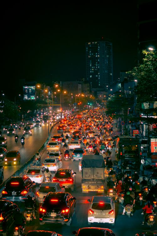 Free A bustling city street with heavy traffic at night, filled with cars and motorcyclists under streetlights. Stock Photo