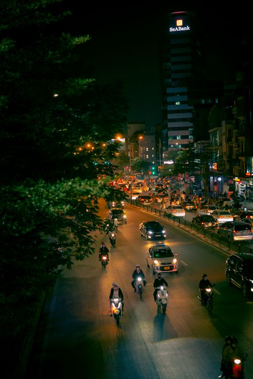 Free A vibrant Hanoi city street scene with motorbikes and cars at night, showcasing urban life. Stock Photo