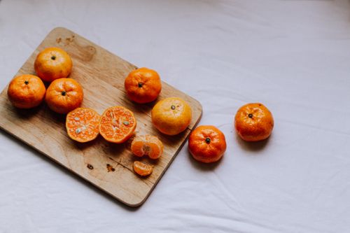 Free Fresh tangerines arranged on a wooden cutting board with a white background, perfect for healthy snack themes. Stock Photo