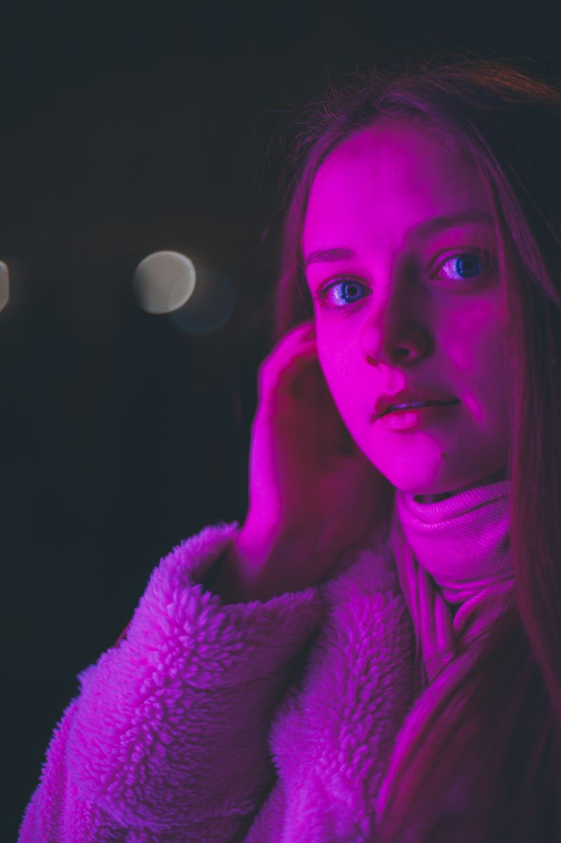 Portrait of a woman in a faux fur coat under neon pink light — photo by Roman Tymochko on Pexels