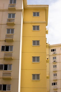Photograph of a modern yellow apartment building featuring multiple windows and balconies.