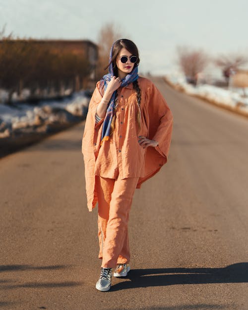 Woman in Orange Outfit Standing on the Road