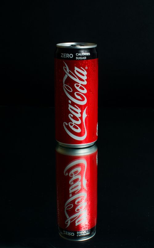Free Close-up of a Coca-Cola Zero can with reflection on a dark surface, highlighting the logo and color. Stock Photo