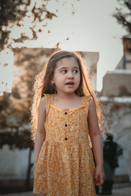 Free Charming portrait of a young girl in a yellow dress, outdoors with soft backlighting. Stock Photo