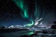 Green Aurora Lights over Snow Covered Mountain during Night Time