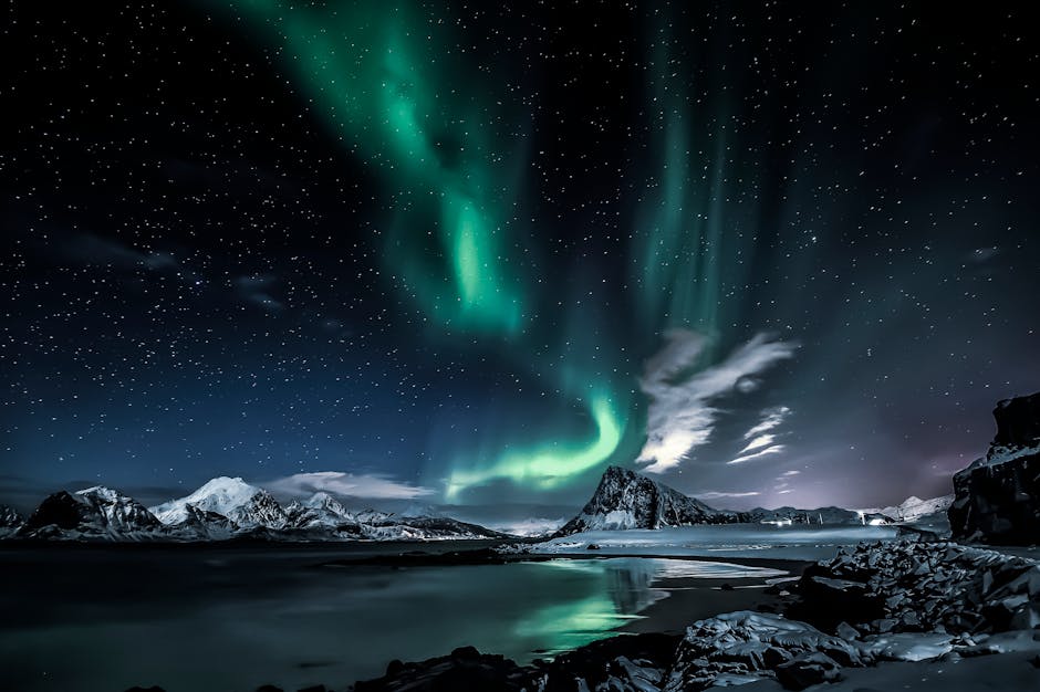 Beautiful northern lights illuminating the starry night over snowy peaks in Nordland, Norway.