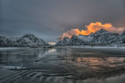 A stunning winter sunset over snow-capped mountains in Nordland, Norway.