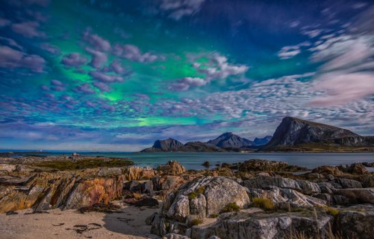 Vibrant aurora borealis lights up the night sky over rocky terrain in Nordland, Norway.