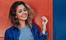 一位穿着牛仔夹克的女人，在充满活力的红蓝背景下灿烂地微笑着