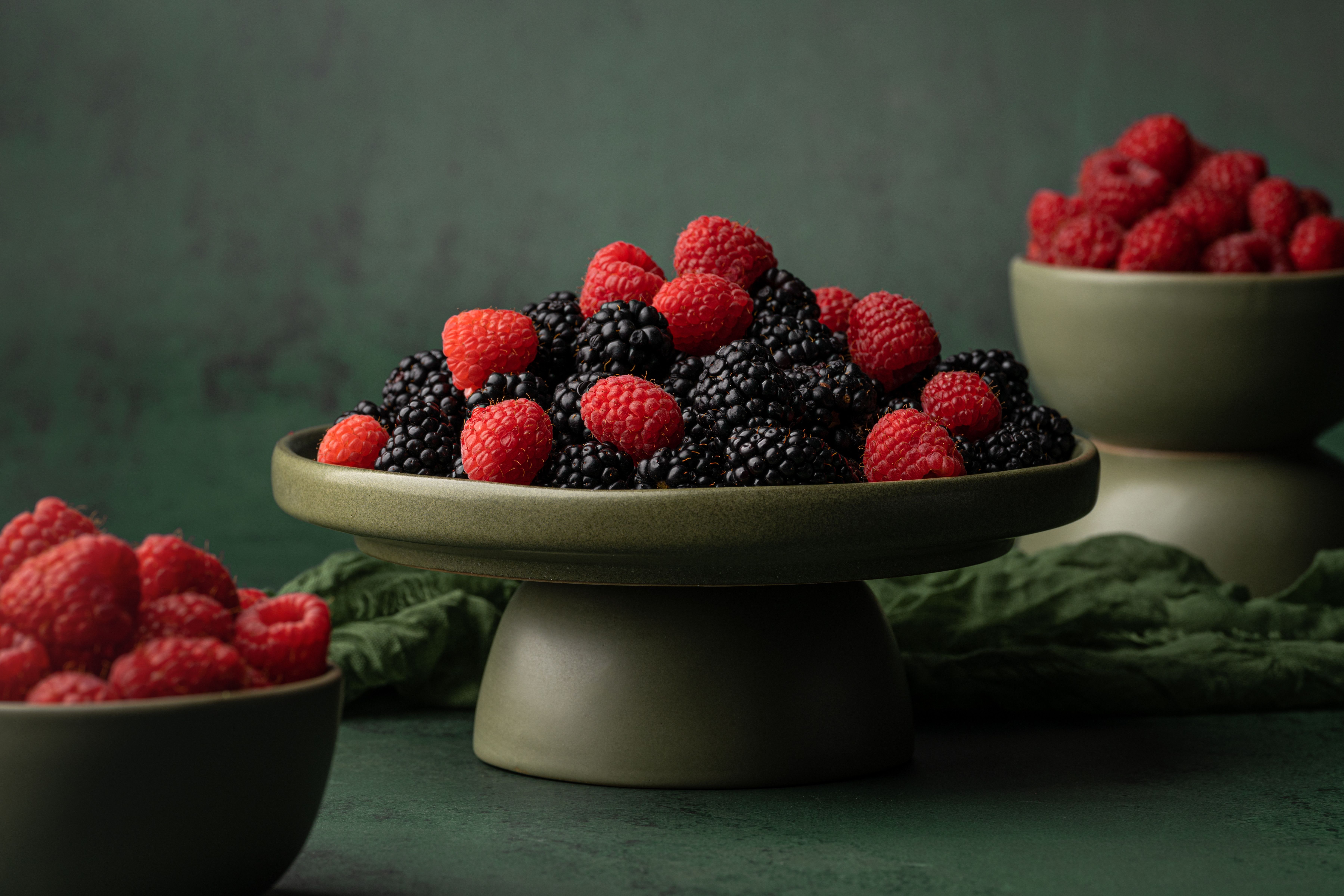 Close-up of fresh raspberries and blackberries in ceramic bowls, perfect for healthy eating concepts.
