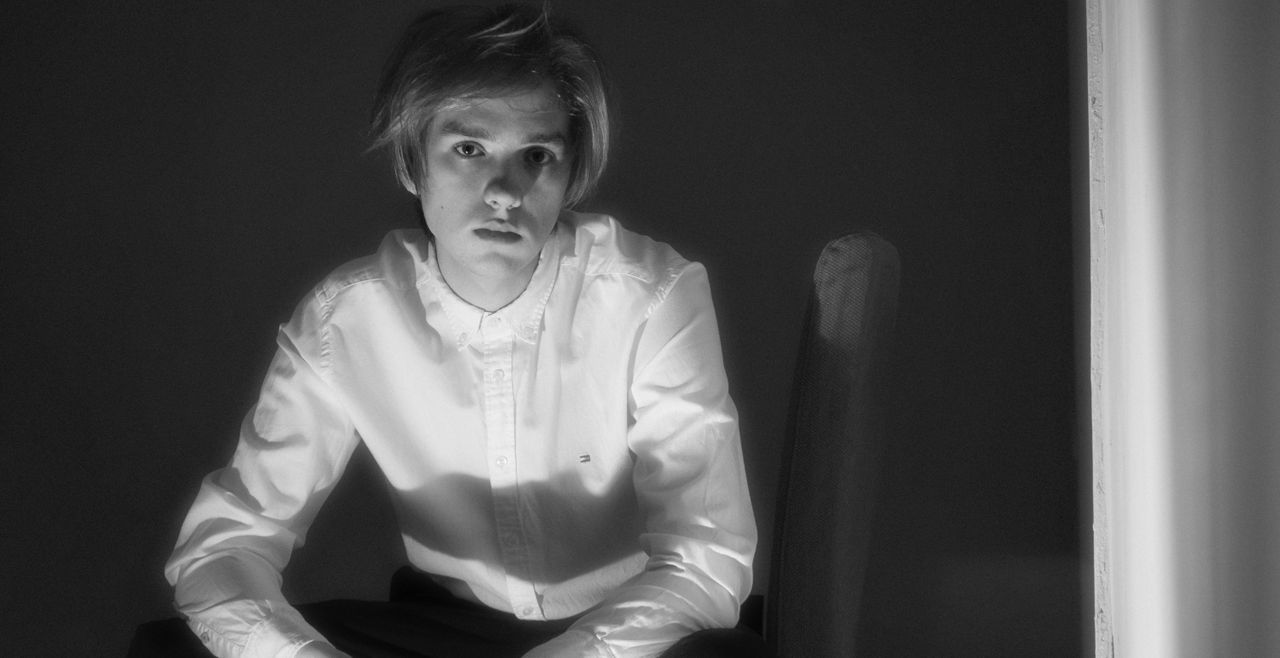 black and white portrait of a man in a white shirt sitting with an int
