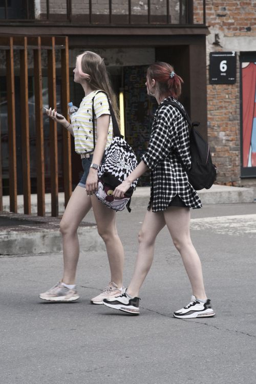Free Two young women walking on a street in Moskva, Russia, wearing casual attire and carrying backpacks. Stock Photo