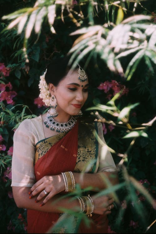 Woman in Traditional Dress Standing Beside Flowering Plants
