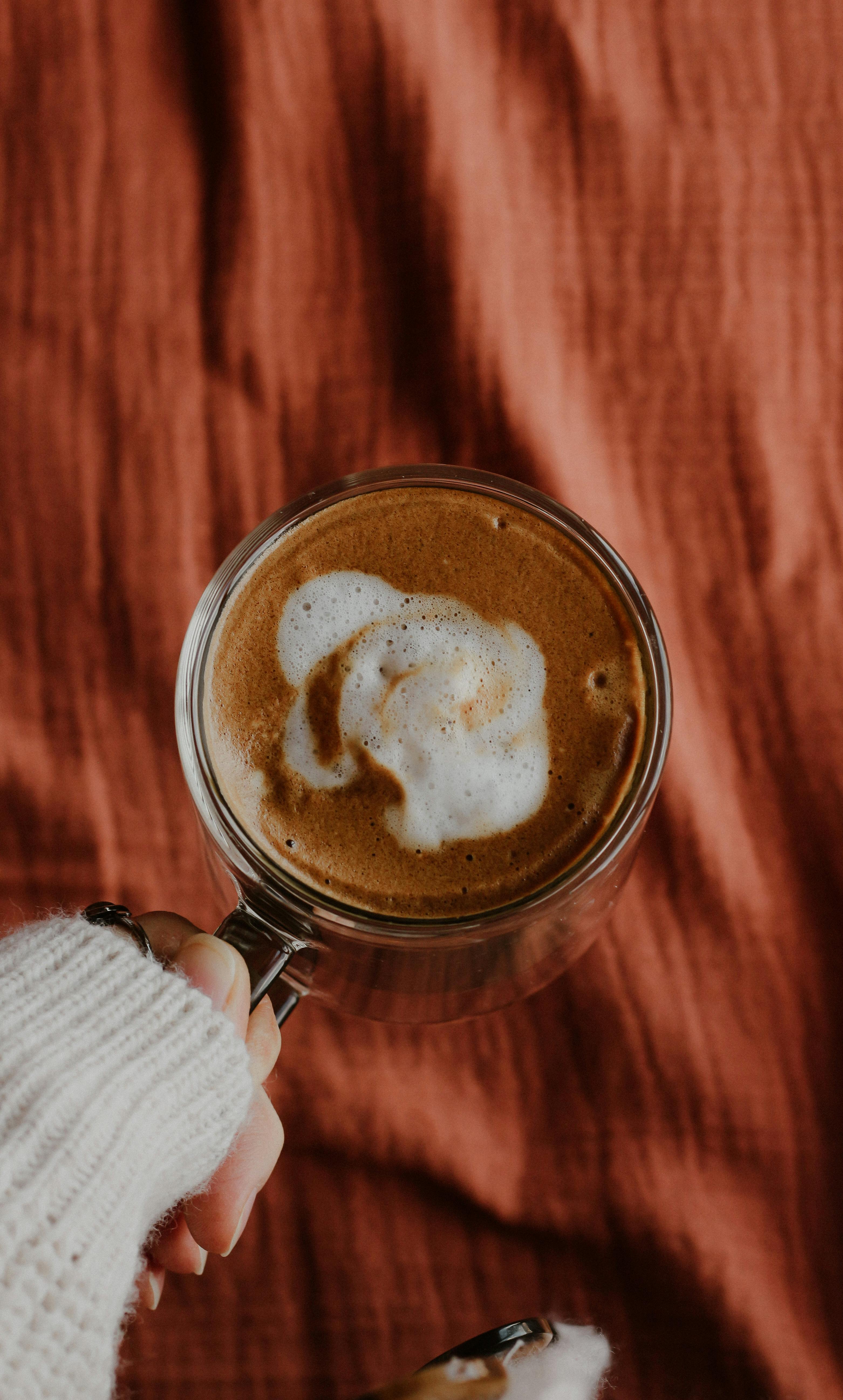 Warm autumn coffee held in a cozy sweater-clad hand, perfect for chilly days.