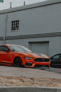 A striking orange sports car parked along a city street, showcasing luxury and power.