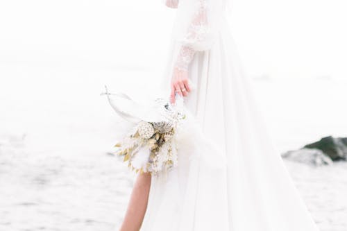 Woman in White Wedding Dress Holding Bouquet of Flowers