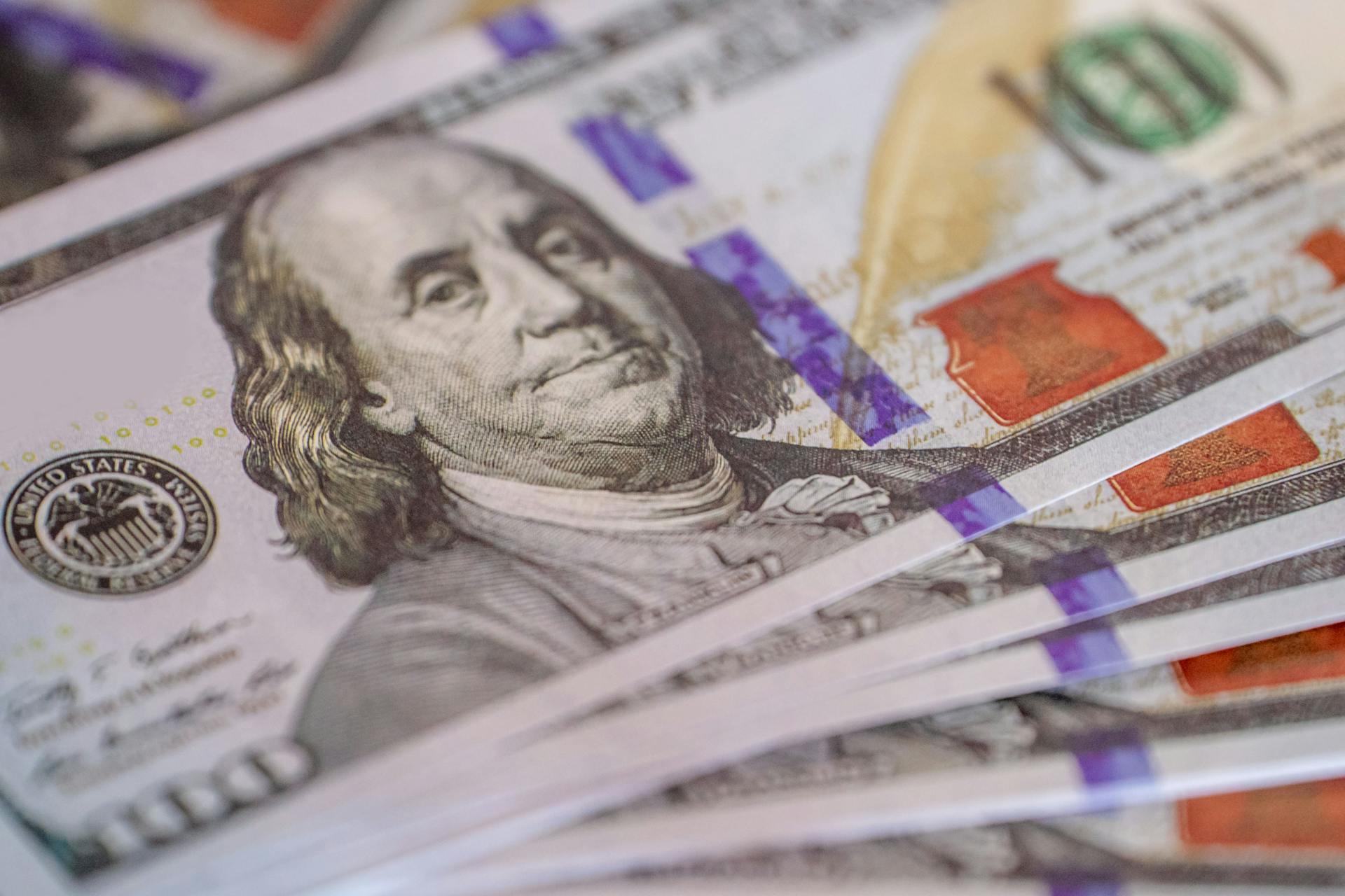 Detailed close-up image of US hundred dollar bills fanned out, showcasing currency detail.