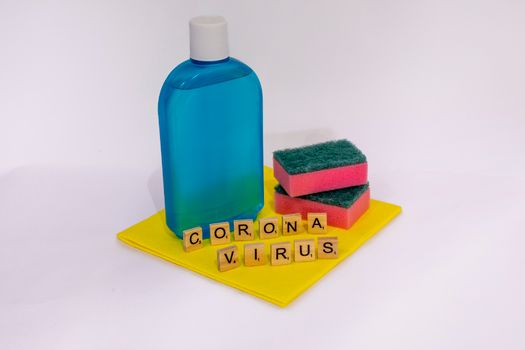 Cleaning products with scrabble tiles spelling 'coronavirus' on a white surface.