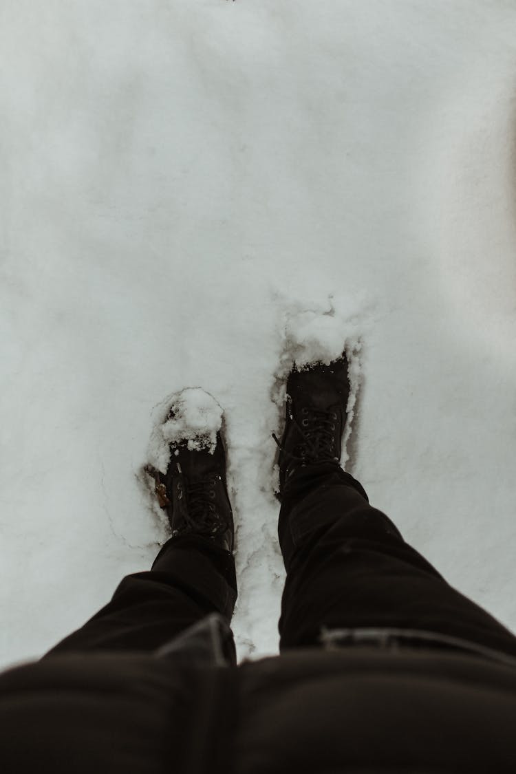 A Person In Brown Pants And Brown Shoes Standing On Snow Covered Ground