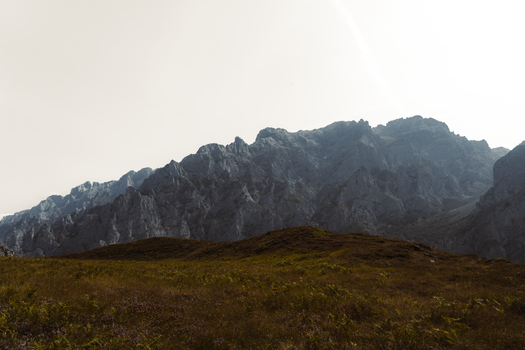 Dramatic view of Spanish mountains under a clear sky, showcasing rocky peaks and lush foreground.